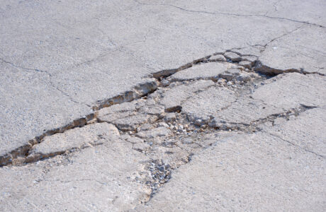 The old badly damaged concrete street background with collapsed and broken crack texture on surface