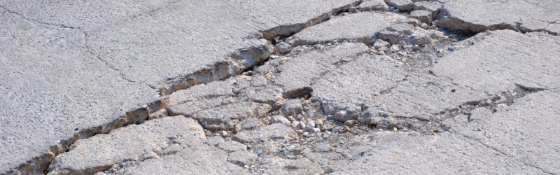 The old badly damaged concrete street background with collapsed and broken crack texture on surface